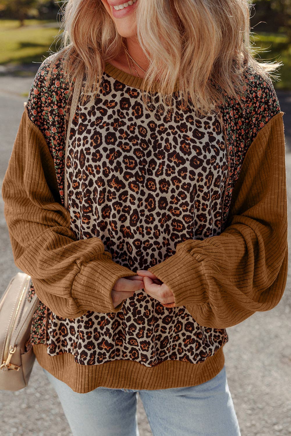 Person wearing a brown sweater with leopard print accents outdoors