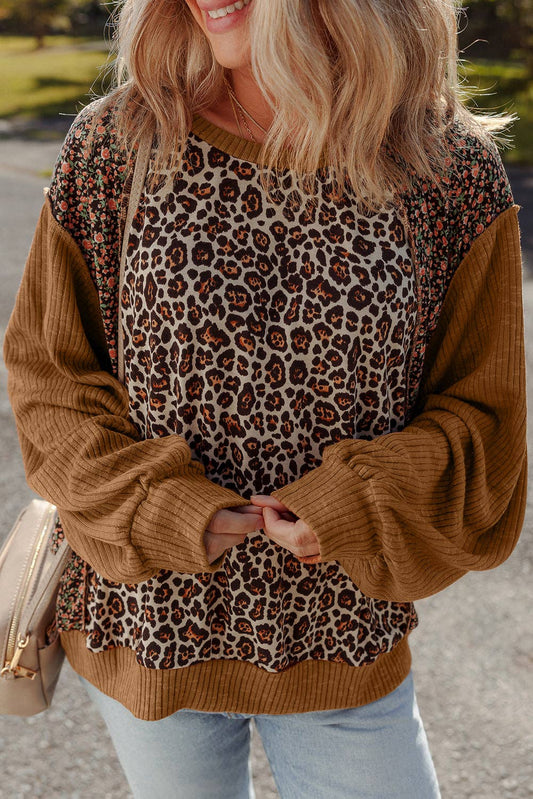 Person wearing a brown sweater with leopard print accents outdoors