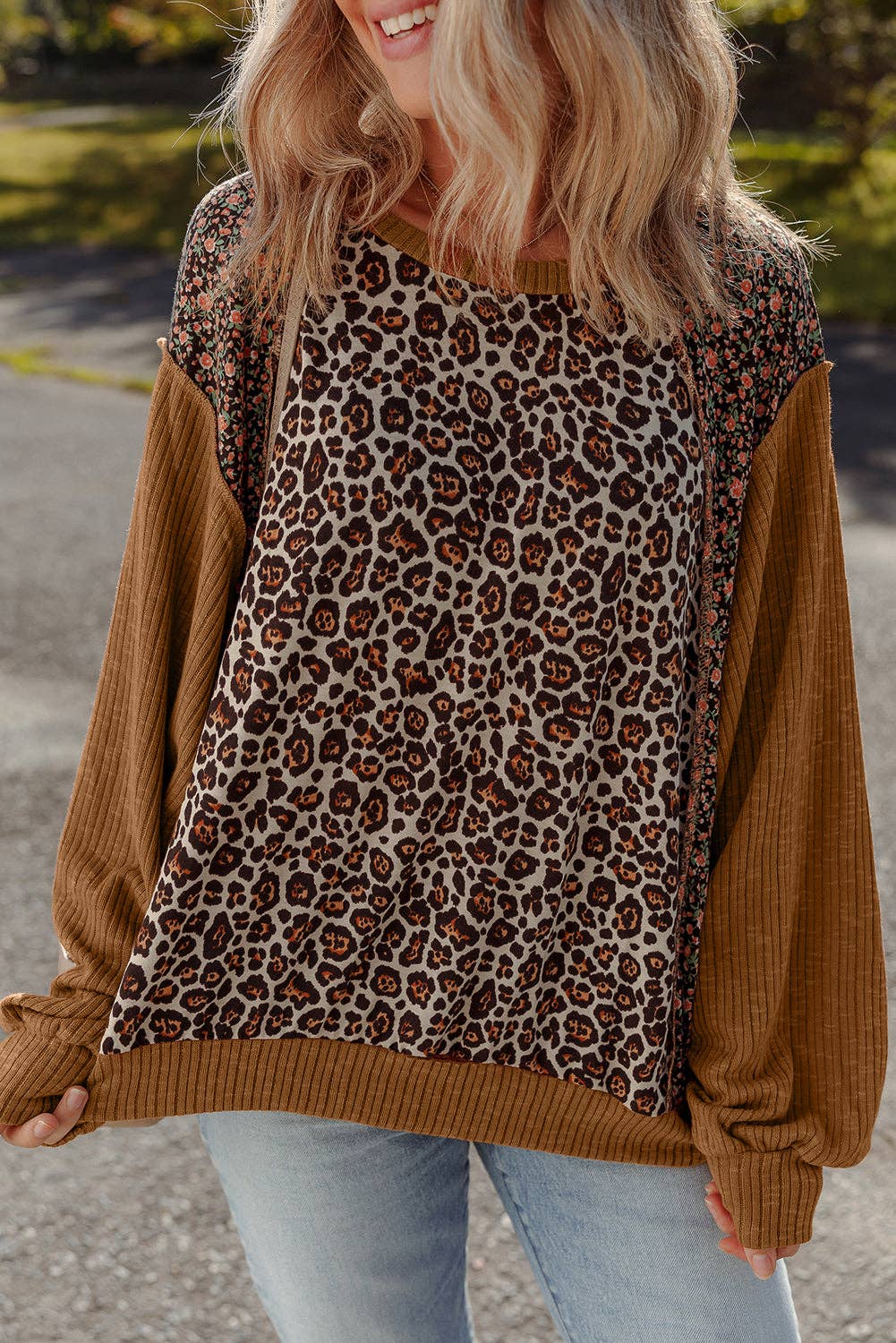Person wearing a sweater with leopard print and brown sleeves outdoors