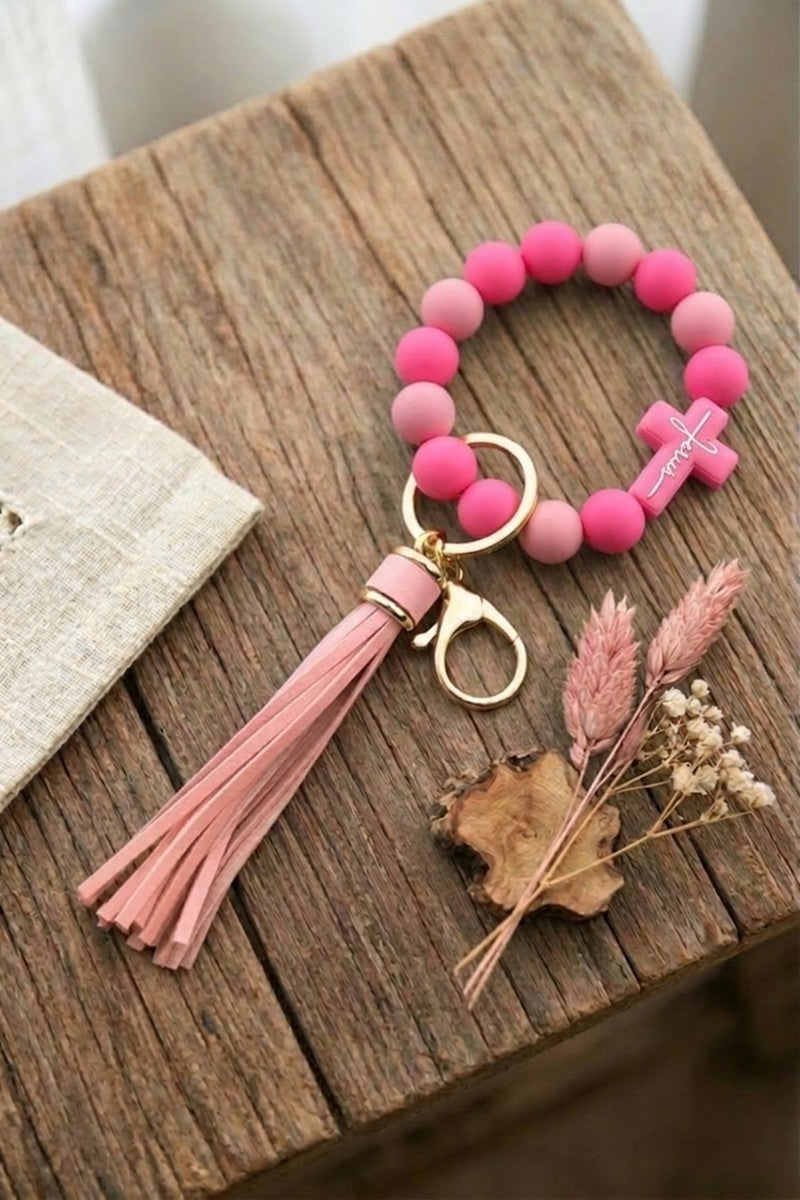 Pink beaded keychain with tassel on a wooden surface