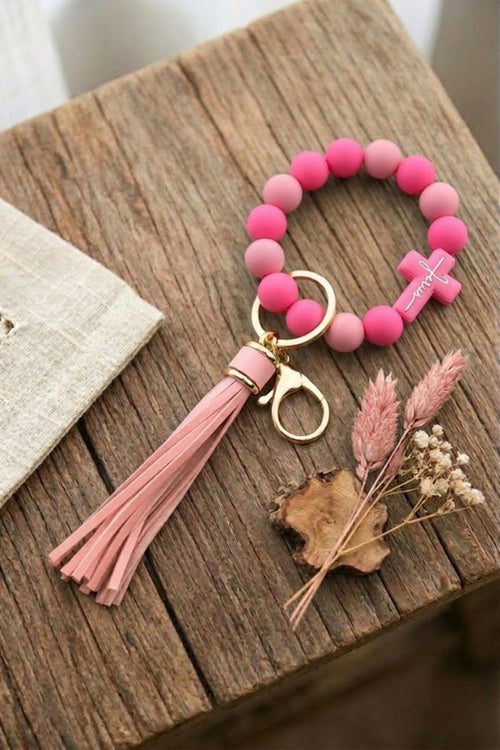Pink beaded keychain with tassel on a wooden surface