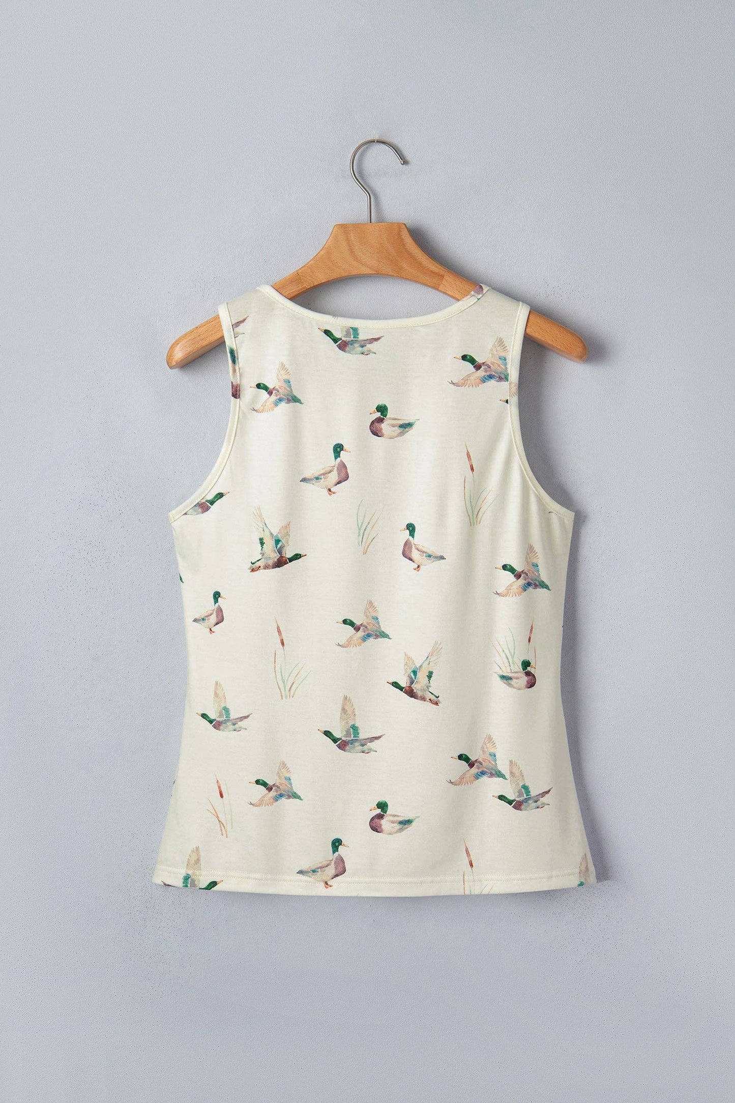 White tank top with duck pattern on a wooden hanger against a gray background