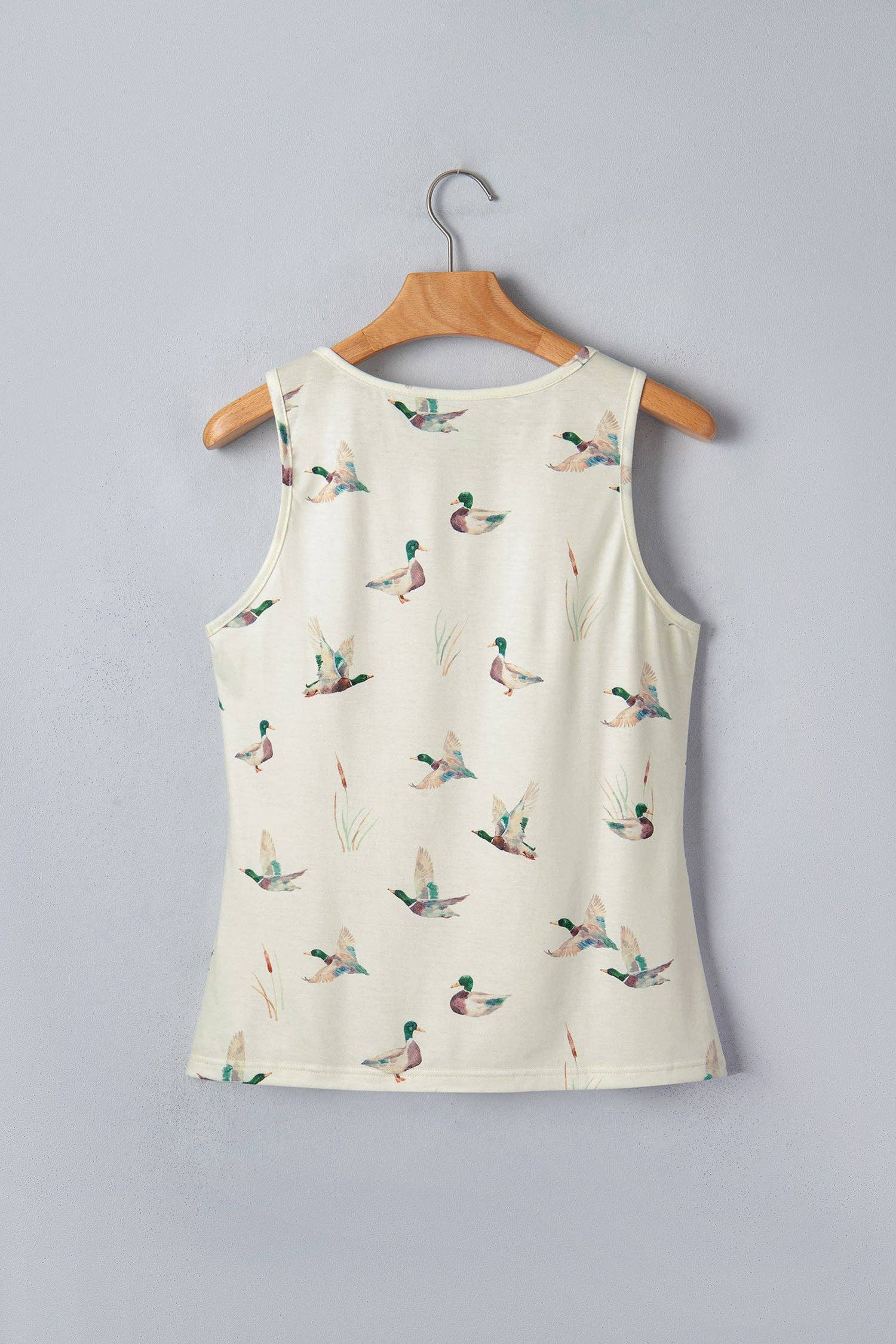 White tank top with duck pattern on a wooden hanger against a gray background