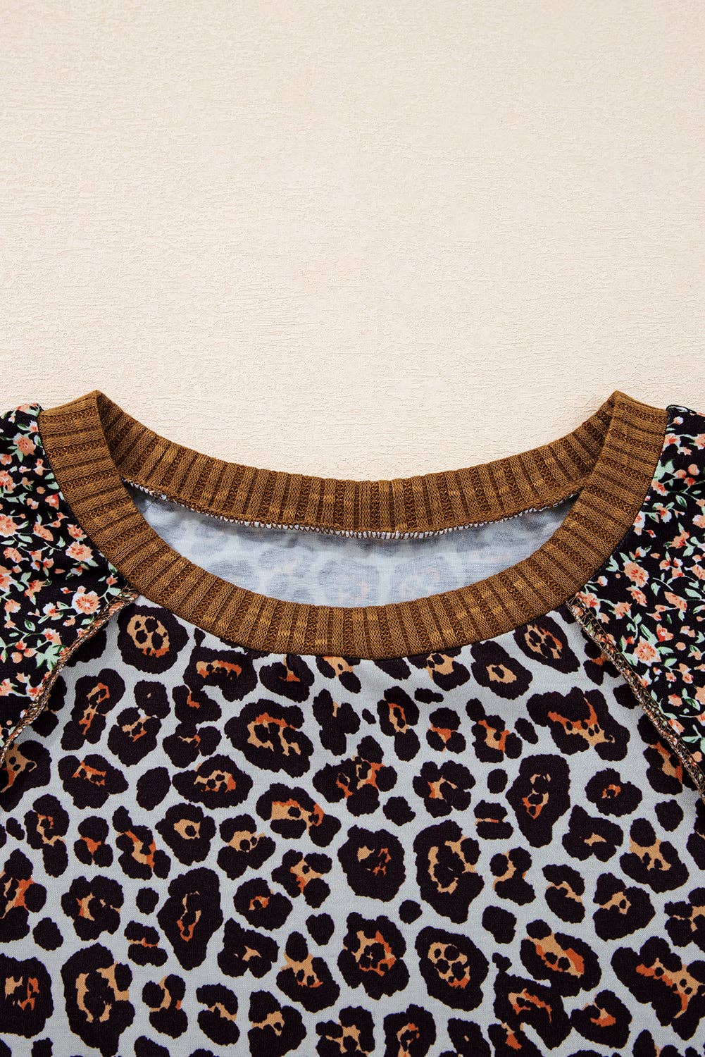 Close-up of a garment with leopard print and brown ribbed neckline on a beige background