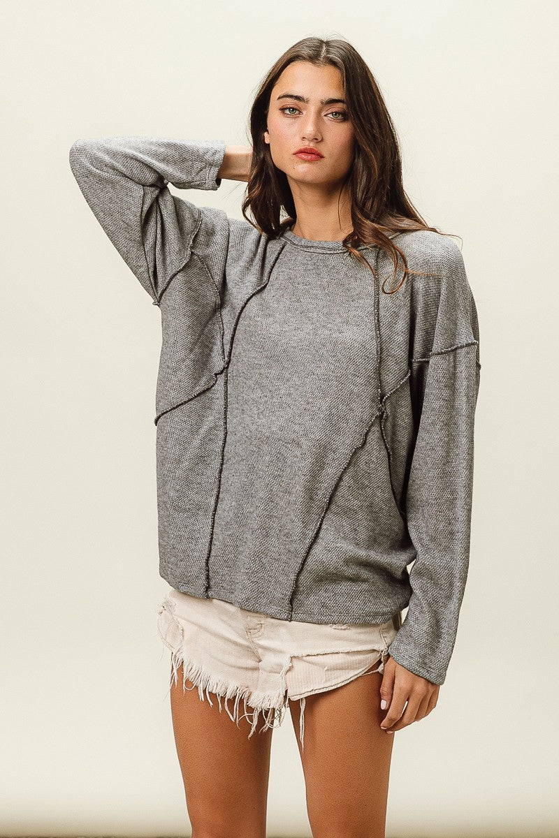 Woman wearing a gray sweater and white shorts on a beige background