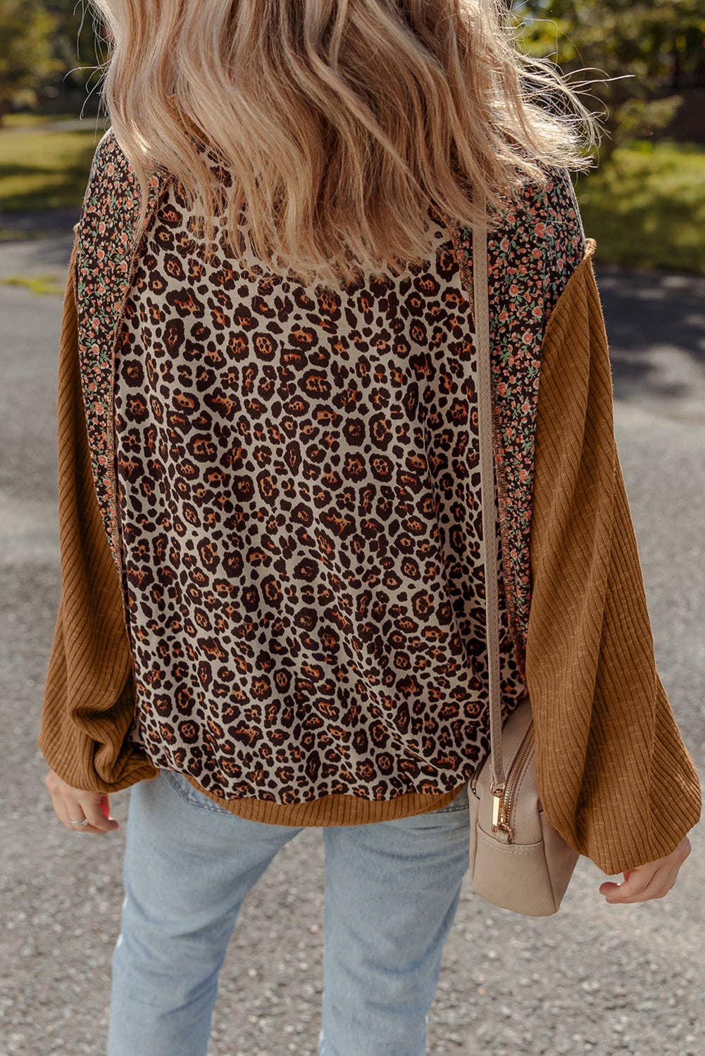 Person wearing a leopard print sweater with brown sleeves outdoors